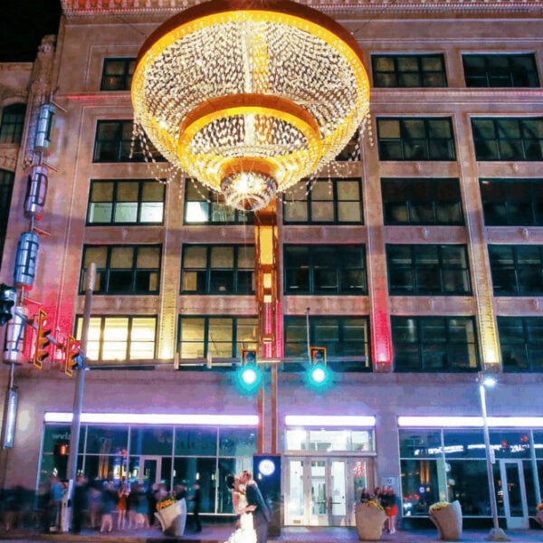 Chandelier installation on an urban building facade at night for event lighting elevation.